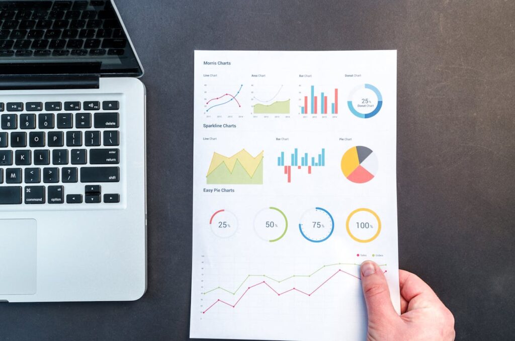 A LAPTOP AND A GRAPH IN A WHITE HAND